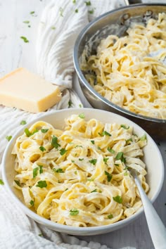 two bowls filled with pasta and cheese on top of a white cloth next to a silver pan