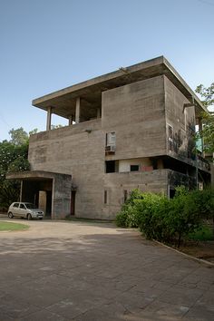 a car is parked in front of a large concrete building with two stories on the second floor