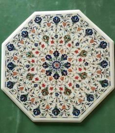 a white plate with blue and red flowers on the inside, sitting on a green surface