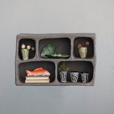 an assortment of vases and plants are arranged in a concrete tray