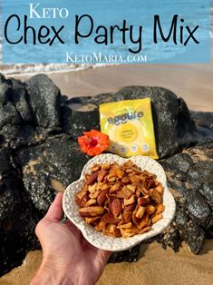 a hand holding a bowl of nuts on the beach with text overlay reading keto chex party mix