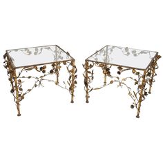 a pair of metal and glass side tables with flowers on the top, one is turned upside down