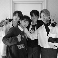 black and white photograph of four young men posing for the camera with one pointing at the camera