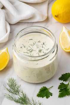 a jar filled with dressing next to lemons and parsley