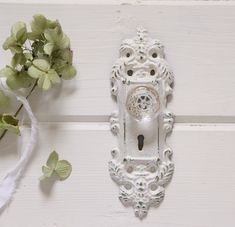 a white door handle with a clock on it next to some flowers and greenery