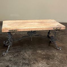 an old wooden table with wrought iron legs and a wood slab on the top that has been turned into a coffee table