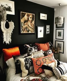 a bed topped with lots of pillows next to pictures