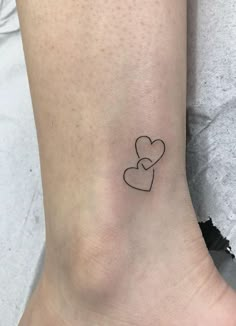 a small tattoo on the ankle of a woman with a heart and two smaller hearts