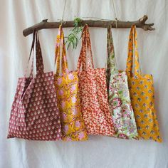 five bags hanging from a tree branch on a white background, each with different patterns