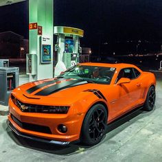 an orange sports car parked at a gas station