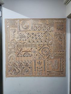 an intricately designed wooden panel hanging on the side of a wall in a room