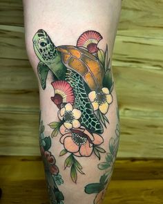 a tattoo on the leg of a woman with flowers and a sea turtle in it