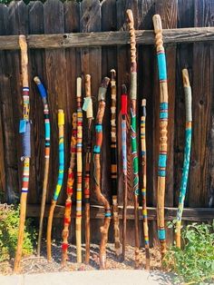 many different colored sticks are lined up next to a wooden fence with grass and flowers