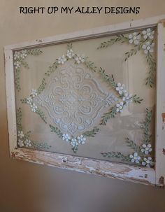 an old window is decorated with white flowers and green leaves in the center, along with words that read right up my alley designs