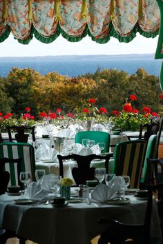 an outdoor dining area with tables and chairs overlooking the ocean in front of a window