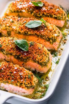 baked salmon fillets with herbs and seasoning in a white casserole dish