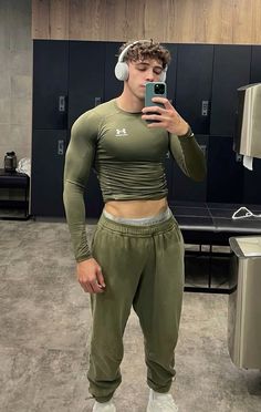 a man wearing headphones taking a selfie with his cell phone in a locker room