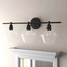 three light fixtures mounted on the wall above a mirror