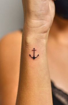 a woman's wrist tattoo with an anchor on the left side of her arm