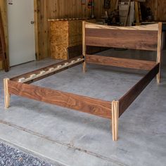 a wooden bed frame sitting on top of a cement floor