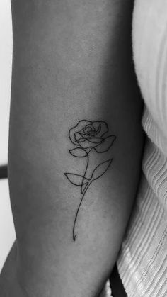 a black and white photo of a single rose tattoo