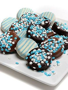 chocolate covered donuts with blue and white sprinkles are on a plate