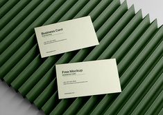 two business cards sitting on top of green wavy lines in front of a white background