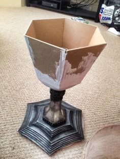 a metal vase sitting on top of a carpeted floor