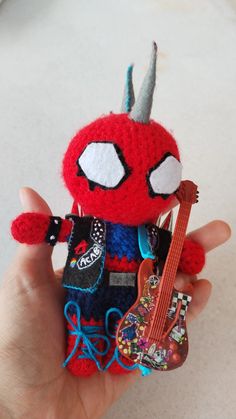 a hand holding a tiny toy with a guitar in it's left hand and a spiderman on the right