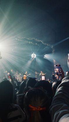 a group of people standing around each other in front of a stage with bright lights