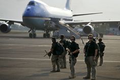 some soldiers are standing in front of an airplane on the tarmac at an airport