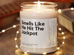 a candle that is sitting on a table with some lights around it and the words smells like he hit the jackpot