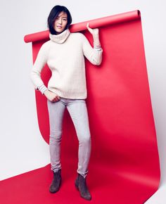 a woman standing in front of a red backdrop holding onto a large roll of paper