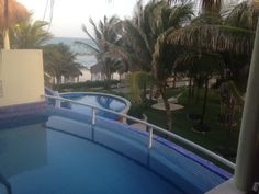 an outdoor swimming pool with palm trees and the ocean in the background