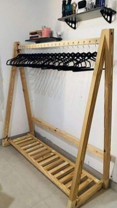 a wooden rack with clothes hanging from it's sides in a white walled room