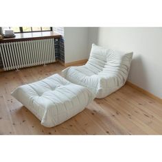 a white futon sofa sitting on top of a wooden floor next to a radiator