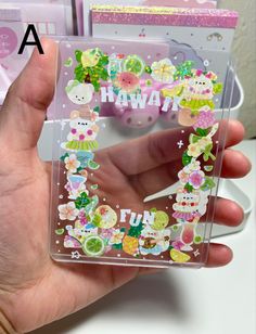 a person holding up a clear case with stickers on it