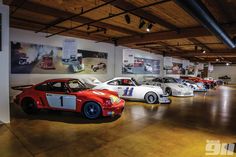 a group of cars parked in a garage next to each other with pictures on the wall behind them