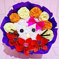 a bouquet of flowers with a hello kitty face on it's head in purple paper