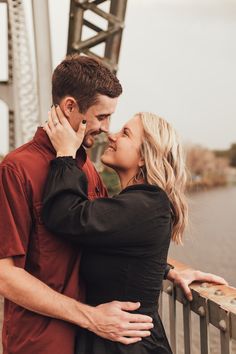 a man and woman standing next to each other on a bridge