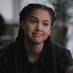 a young woman with braids smiling at the camera while sitting in front of a table