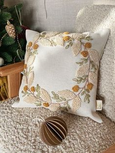 a white pillow with yellow flowers on it next to a christmas tree and other decorations