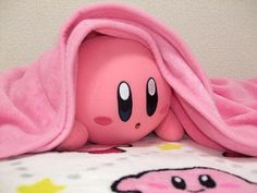 a close up of a stuffed animal under a pink blanket on a bed with stars