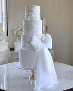 a three tiered white wedding cake sitting on top of a table