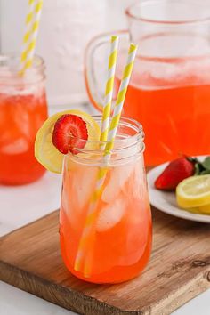 two glasses filled with lemonade and strawberries on top of a wooden cutting board