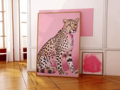 a cheetah sitting on the floor in front of a pink wall with two paintings