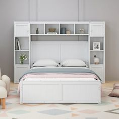 a white bed sitting next to a chair and book shelf in a room with a rug on the floor