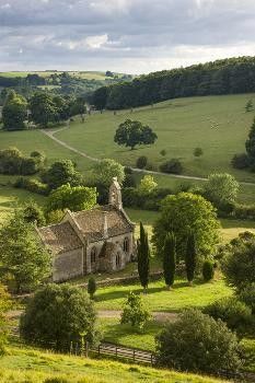 an old church in the middle of a lush green valley surrounded by trees and rolling hills