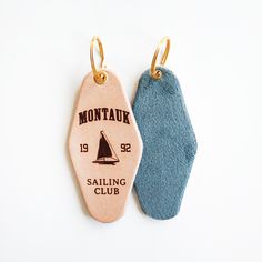 two wooden tags with sailboats on them sitting next to each other in front of a white background