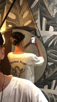 a woman taking a selfie in front of a mirror while wearing a white shirt